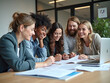 © Ali - Smiling group of diverse businesspeople going over paperwork together and working on a laptop at a table in an office