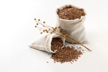 two bags of raw flaxseeds and flaxseed spikes on white background.