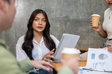 A gorgeous Asian businesswoman is focused on listening to her colleague's ideas in the meeting.