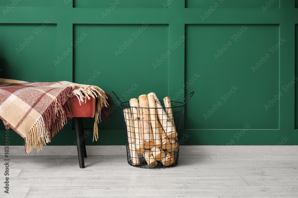 Bench with warm blanket and firewood near green wall