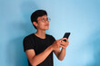 © Muhamad  - Young Asian man thinking about something while holding a mobile phone