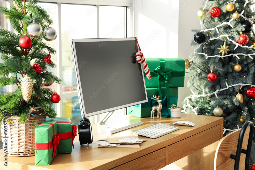 Workplace with computer monitor, presents and Christmas tree in office