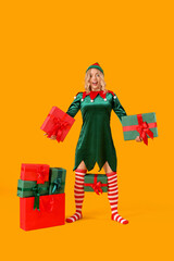 Sticker - Happy young woman dressed as elf with Christmas gifts on yellow background