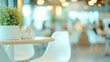 © Arifin Studio - A close up of a white table and chairs in a cafe with a blurred background of other people.