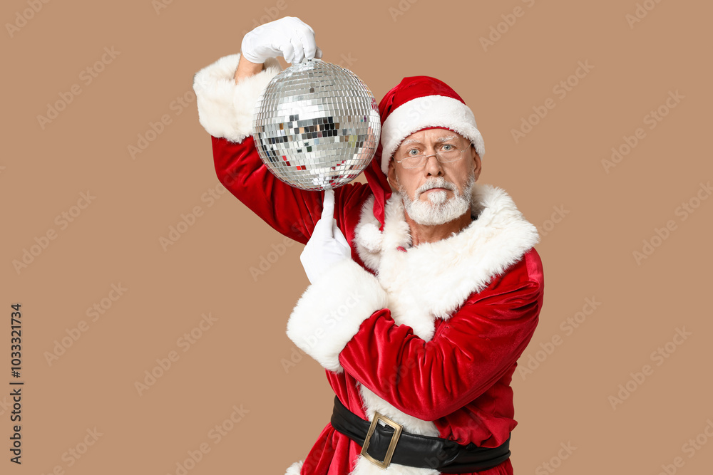 Santa Claus in glasses pointing at disco ball on brown background