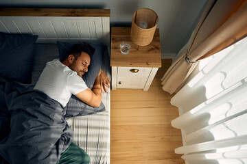 Wall Mural - Above view of man sleeping on bed at home.