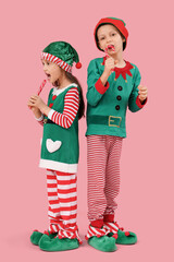 Poster - Cute little children in elf's costumes with candy canes on pink background