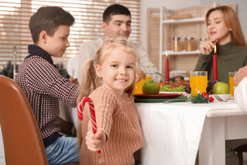 Canvas Print - Little girl with candy cane having family dinner at home on Christmas eve