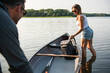 © Cavan Images - Smiling woman loading backpack into canoe on summer day