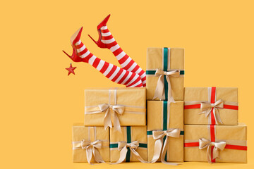 Female legs in Christmas stockings sticking out of different gift boxes on yellow background