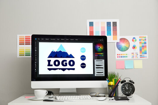 Workplace of graphic designer with modern computer, alarm clock and color charts on white table