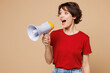 © ViDi Studio - Young smiling happy woman she wear red t-shirt casual clothes hold in hand megaphone scream announces discounts sale Hurry up isolated on plain pastel light beige background studio. Lifestyle concept.