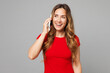 © ViDi Studio - Young smiling fun happy woman she wear red t-shirt casual clothes talk speak on mobile cell phone conducting pleasant conversation isolated on plain grey background studio portrait. Lifestyle concept.