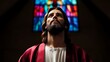 © Helois - A man with long hair and a beard looks up towards stained glass in a church.