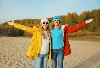 Happy joyful two women friends on sunny beach, stylish girlfriends smiles together on sea coast