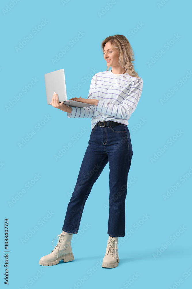 Beautiful young woman using laptop on blue background