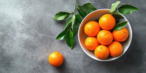 Poster - Mandarins with leaves in a bowl on a gray background.
