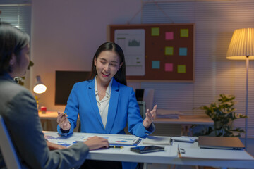 Two Asian businesswomen come up with an idea. Discuss investment projects and strategic planning with information via various documents and files. On a laptop computer at modern office.