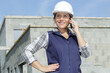 © auremar - worried female contractor wearing hard hat on site using phone