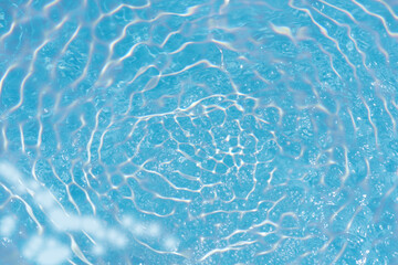 Blue water with ripples on the surface. Defocus blurred transparent blue colored clear calm water surface texture with splashes and bubbles. Water waves with shining pattern texture background.