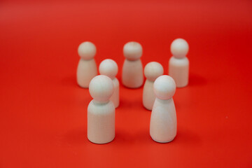 This captivating image portrays a group of white wooden figures gathered together against a vibrant red background. 