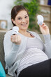 © auremar - pregnant woman holding small baby shoes relaxing at home