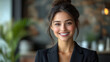 © Inna - Confident businesswoman with updo hairstyle smiling warmly against blurred office backdrop