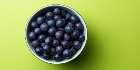 Aufkleber - Top view of small sour blue-black sloes in a bowl on a green background with copyspace.