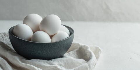 Poster - organic white eggs in a dark gray bowl on a white background with copyspace for text