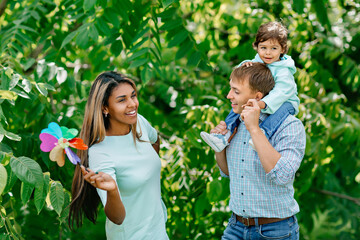 Wall Mural - Black mother, father and child having fun outdoors. Multi-ethnic, African-American and European family hug and laugh in park.