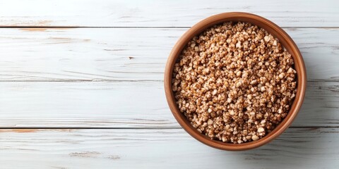 Canvas Print - Brown bowl of delicious buckwheat porridge on a white wooden table. Top view with copyspace.