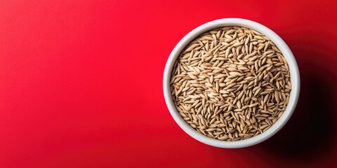 Poster - White cumin seeds, also known as jeera seeds, placed in a white bowl against a red background with copyspace in a horizontal layout.