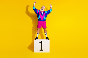 Wall Mural - Full length photo banner of sportive cheerful old man first place pedestal dressed retro sportswear isolated on yellow color background