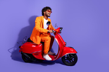 Canvas Print - Full length photo of handsome good mood guy wear orange suit riding moped emtpy space isolated violet color background