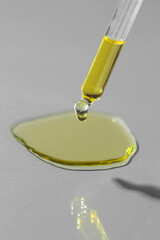 Poster - Dripping essential oil from pipette on grey background, closeup