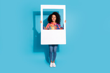 Poster - Full length photo of lovely young lady hold instant photo frame dressed stylish colorful garment isolated on blue color background