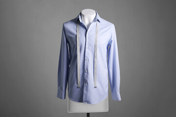 Wall Mural - Male mannequin with light blue shirt and measuring tape on grey background