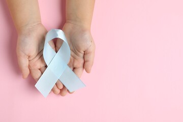 Canvas Print - Child with light blue ribbon on pink background, top view and space for text. Childhood cancer awareness