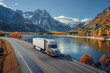 © mankjon - Semi-Truck Traveling on Highway Alongside Scenic Lake and Autumn Mountains
