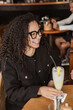 © dolores - Joven latina de pelo rizado bebiendo una piña colada