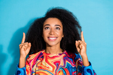 Wall Mural - Photo portrait of beautiful curly hair woman in trendy sweatshirt fingers pointing up hot offer isolated on blue color background