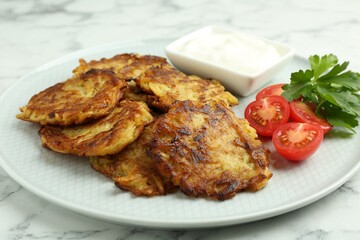 Delicious potato pancakes with fresh tomatoes, sour cream and parsley on white marble table, closeup