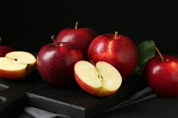 Canvas Print - Whole and cut fresh ripe red apples on black wooden table, closeup