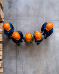 Group of workers in safety helmets collaborating in a warehouse.