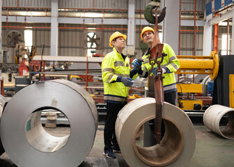 Two professional Asian male engineers analyze an industrial steel lift and inspect its operation.