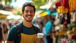 © Lion - Latino man in a vibrant setting at a street market, holding a coffee cup and smiling, background with colorful stalls and people in slight blur, bright daylight