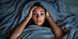 © Sasint - A woman tossing and turning in bed, covering her head with blankets to drown out the sound of her partner'ss snoring, her frustration clear, set in a cozy but dimly lit bedroom