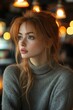 © Charoen - A woman with red hair and a grey sweater is sitting in a cafe
