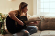 © Malambo/peopleimages.com - Woman, relax and guitar on sofa for music, practice and learning chords in home. Musician, string instrument and strumming in living room with talent, pitch development or rehearsal for performance