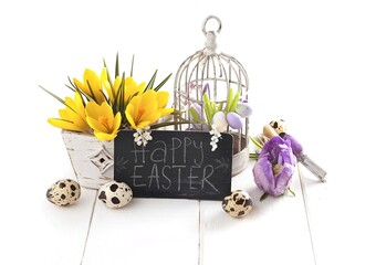 Easter decoration with quail eggs, birdcage, yellow Spring Crocus, and blackboard on wooden white background